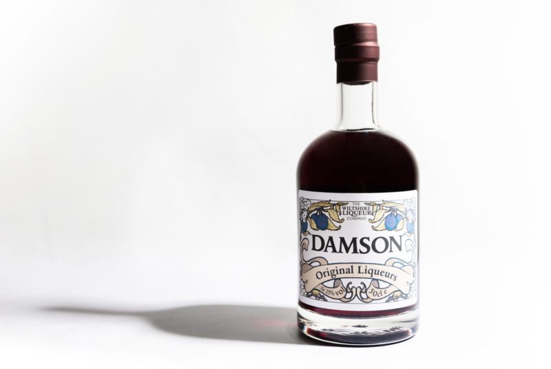 A bottle of The Wiltshire Liqueur Company's Damson Liqueur on a white background.