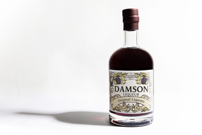 A bottle of Damson Liqueur from the Wiltshire Liqueur Company, on a white background.