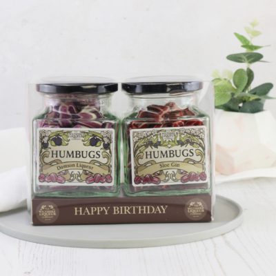 Two jars of Liqueur humbugs with a personalised label that reads: happy birthday. The gift set sits on a white table.